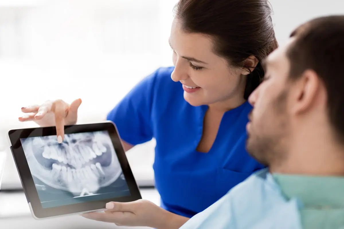 dentist and patient with teeth x ray on tablet pc
