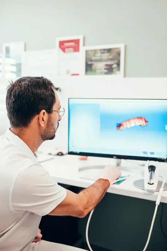 Doctor dentist on a computer models the jaw to develop the shape of a dental implant