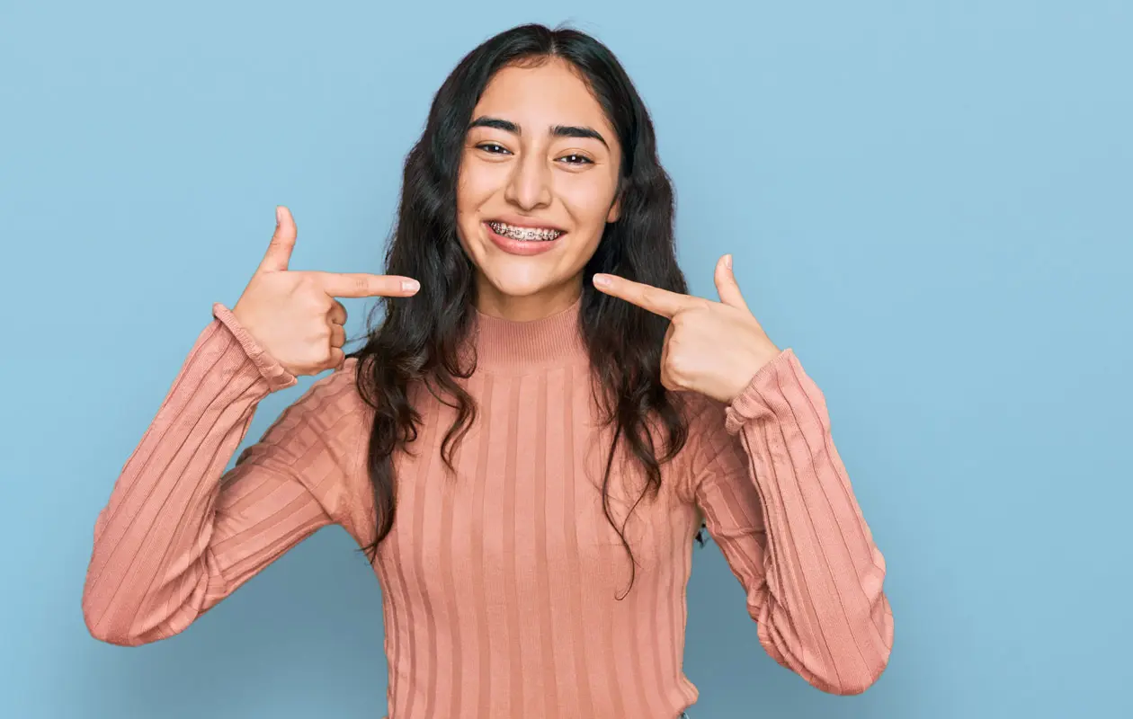 Hispanic teenager girl with dental braces wearing casual clothes smiling cheerful showing and pointing with fingers teeth and mouth. dental health concept. Hispanic teenager girl with dental braces wearing casual clothes smiling cheerful showing and pointing with fingers teeth and mouth. dental health concept.